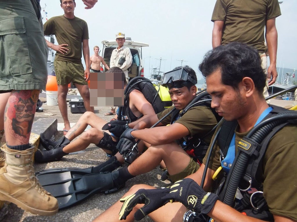 A group of Cambodian men sitting down in diving gear