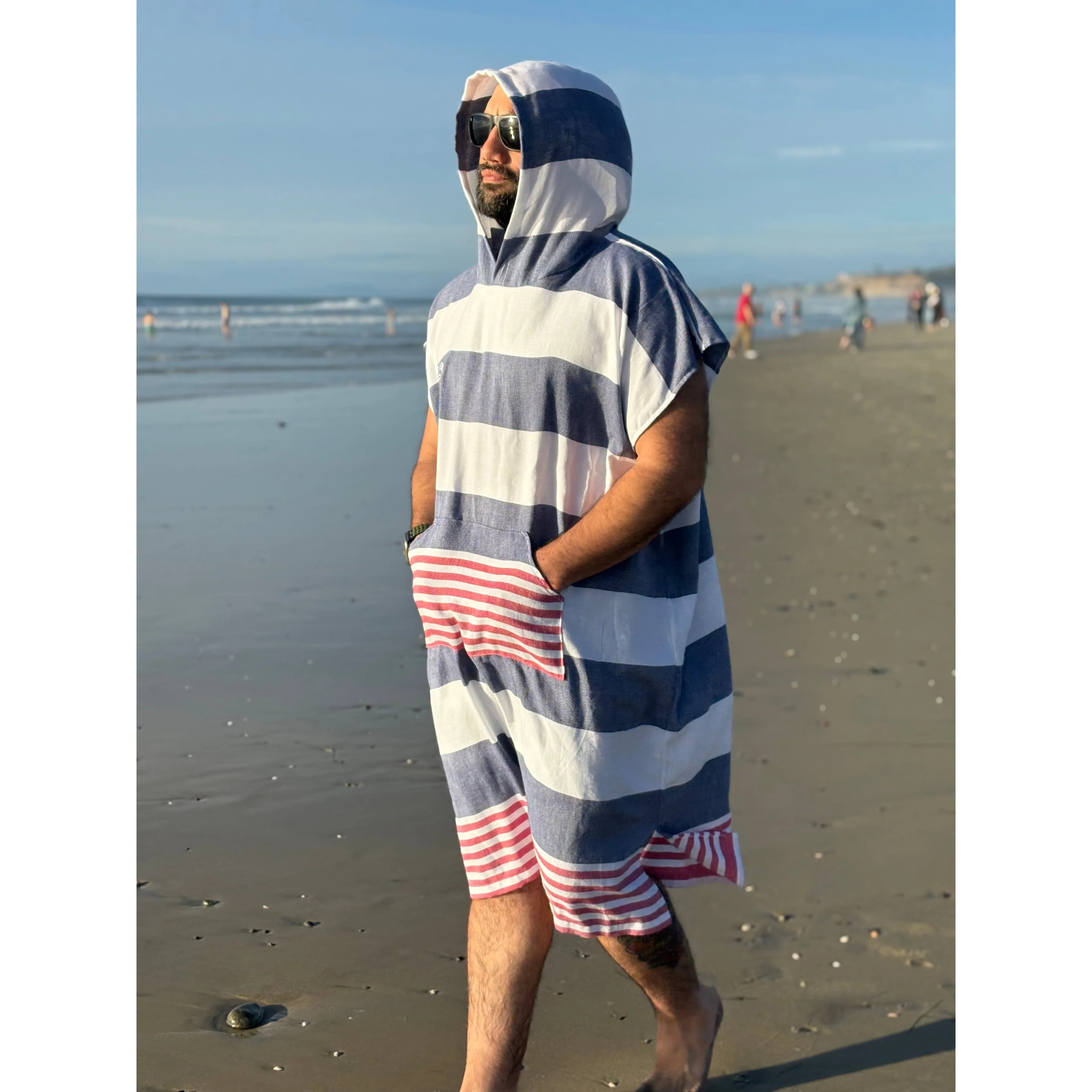 Man wearing a blue and white striped poncho on a beach