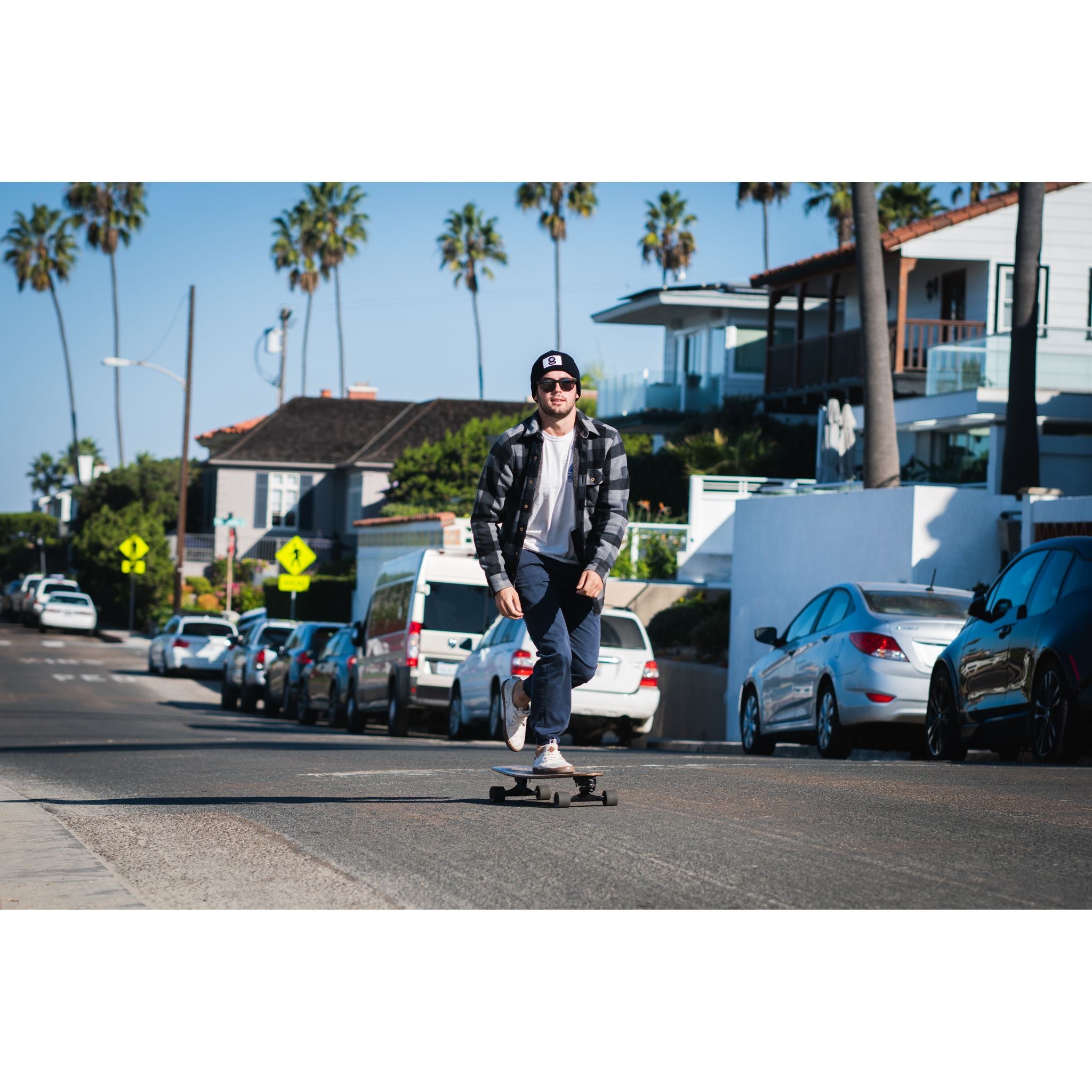 The Watch Cap - man wearing black beanie while skateboarding down the street