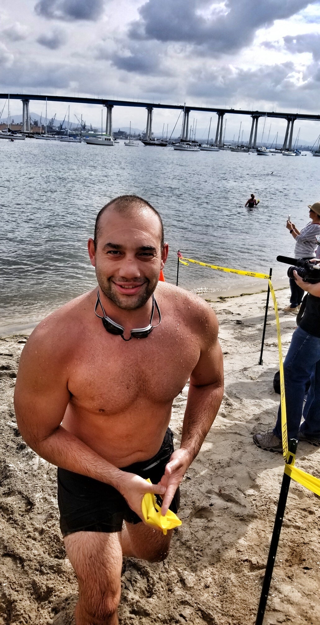 Shirtless man standing on the beach smiling into the camera