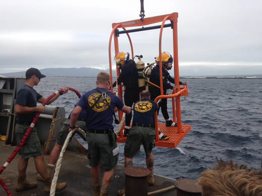 Navy divers getting hoisted out of the water after a dive