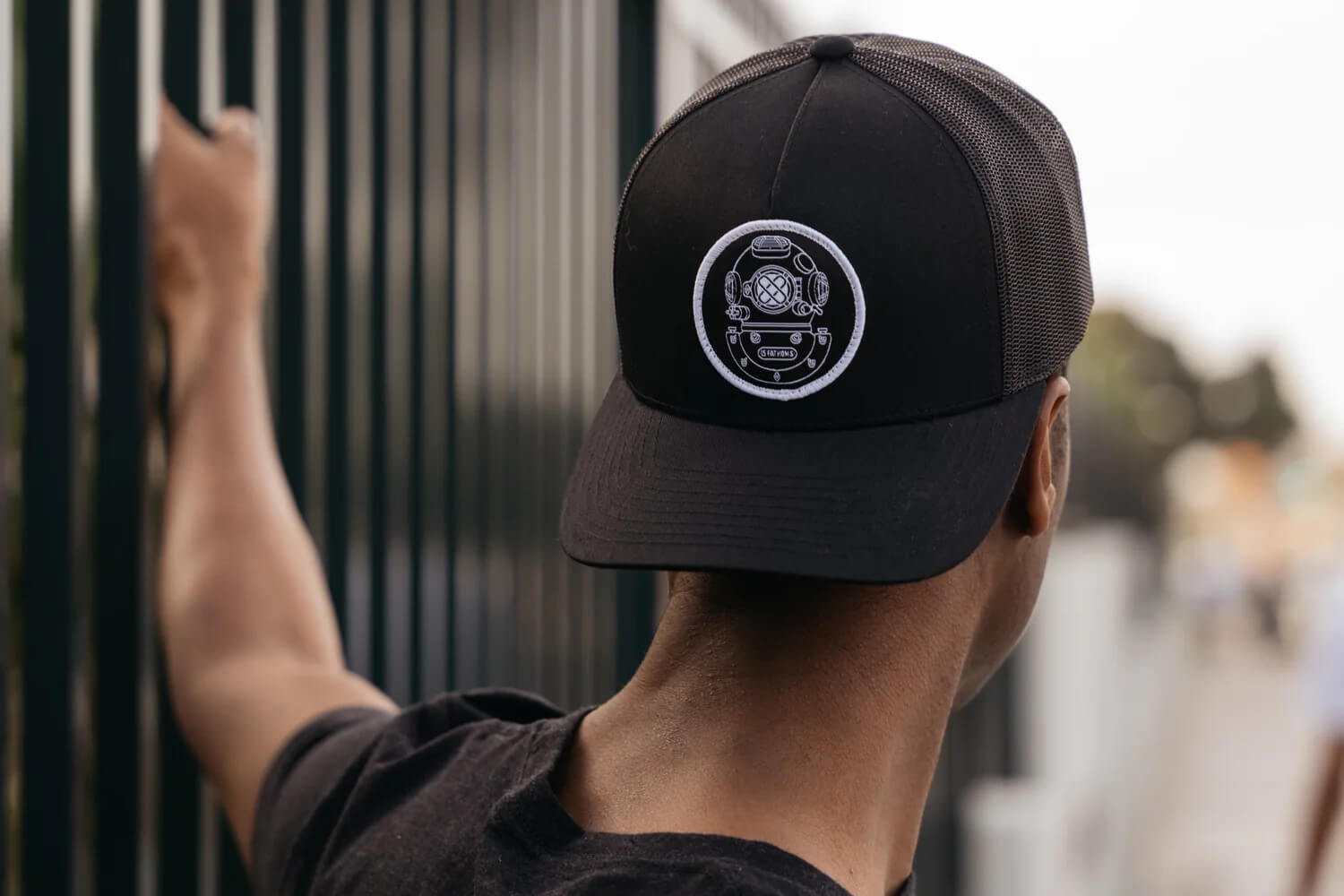 Man looking out wearing a backwards 15 Fathoms hat with diver helmet logo