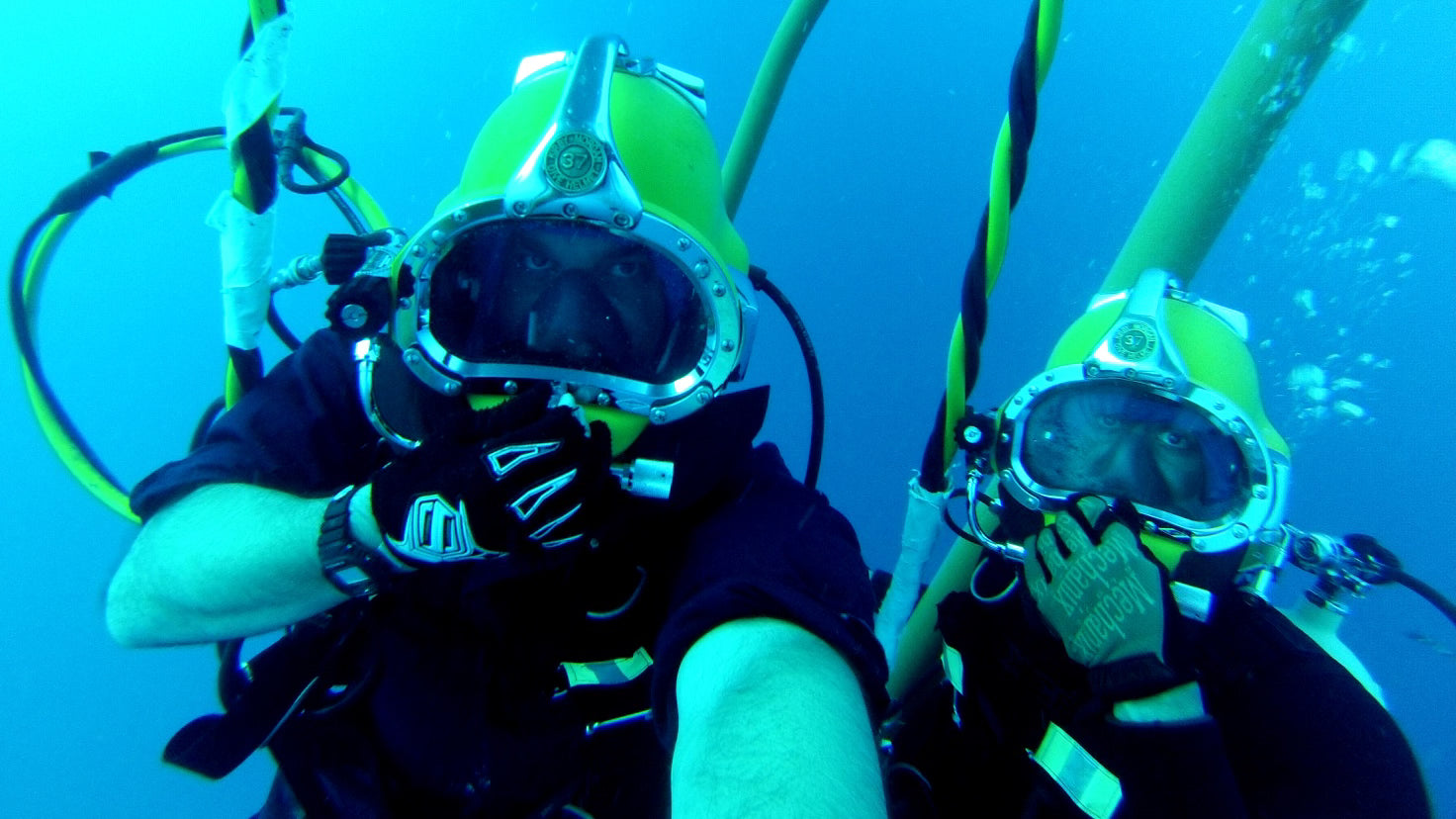 Two scuba divers underwater with diving equipment looking into the camera