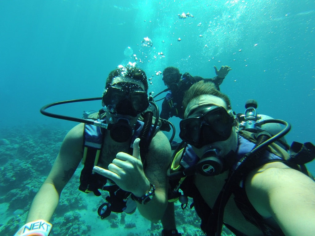 Three scuba divers underwater with equipment posing for the camera