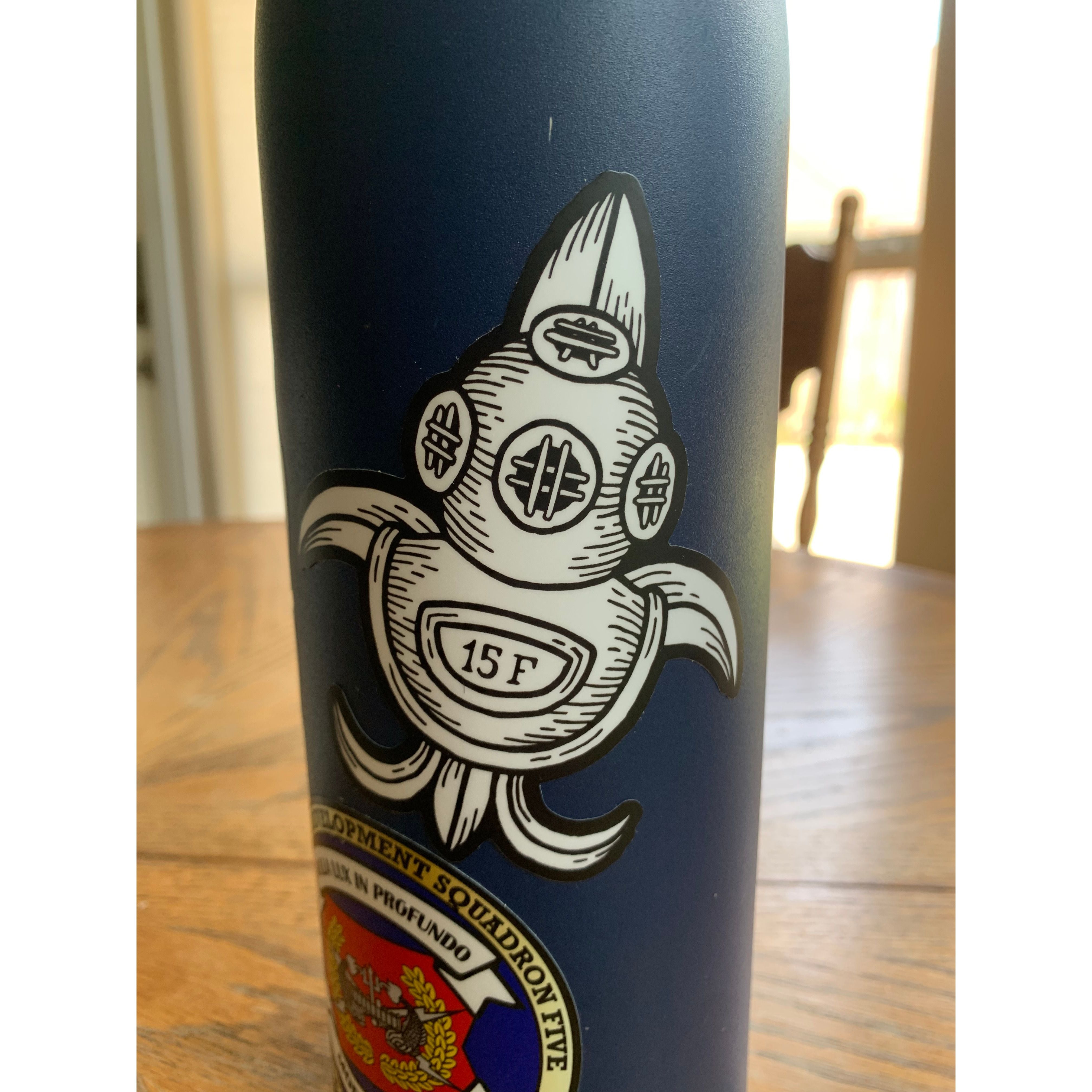 Nola Diver Buddy Pair - dive helmet sticker over a saints logo placed on a canteen