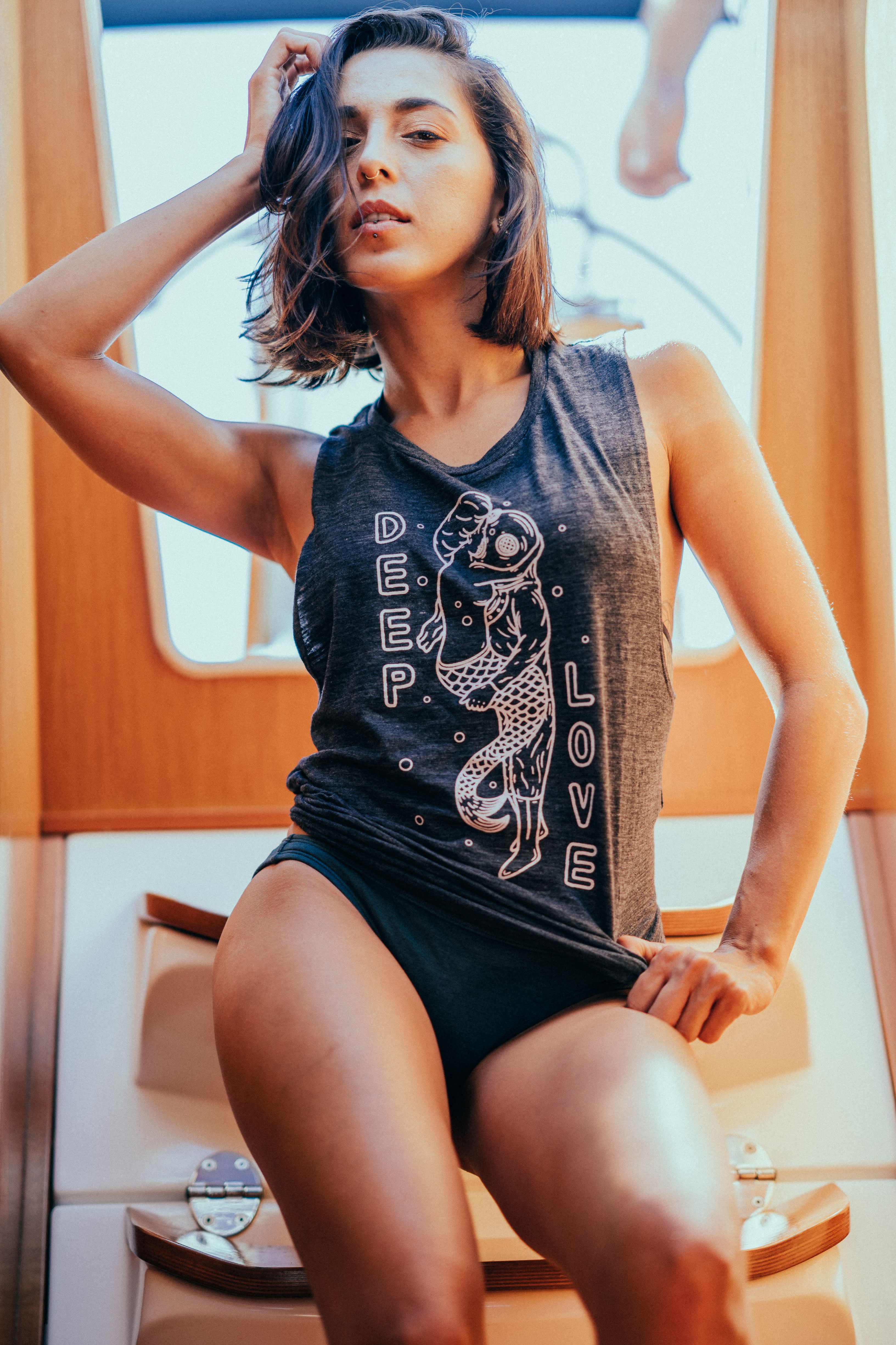 Woman on the steps inside of a sailboat modeling a 15 Fathoms tank top