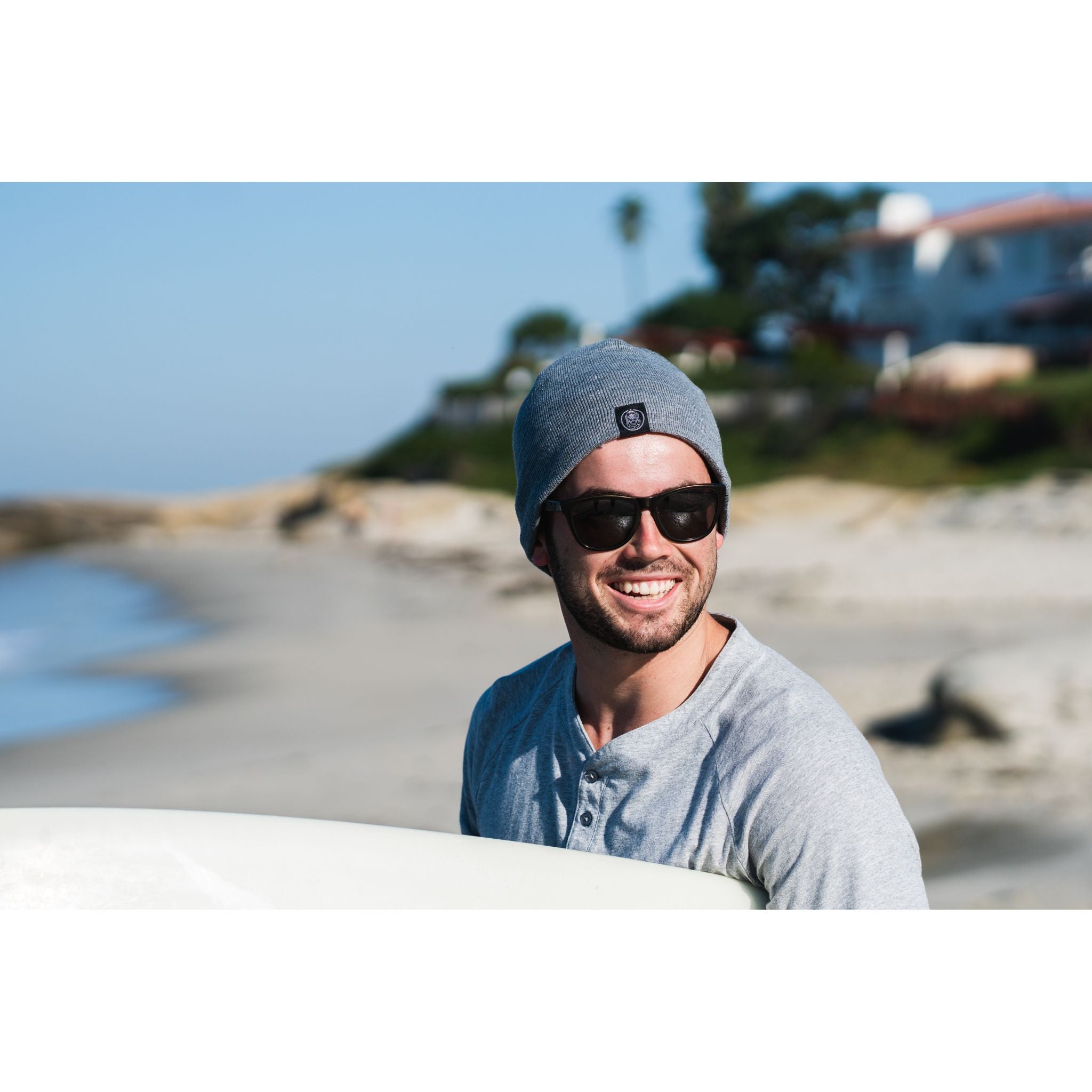 Sport Beanie - man wearing gray beanie while carrying surf board on the beach
