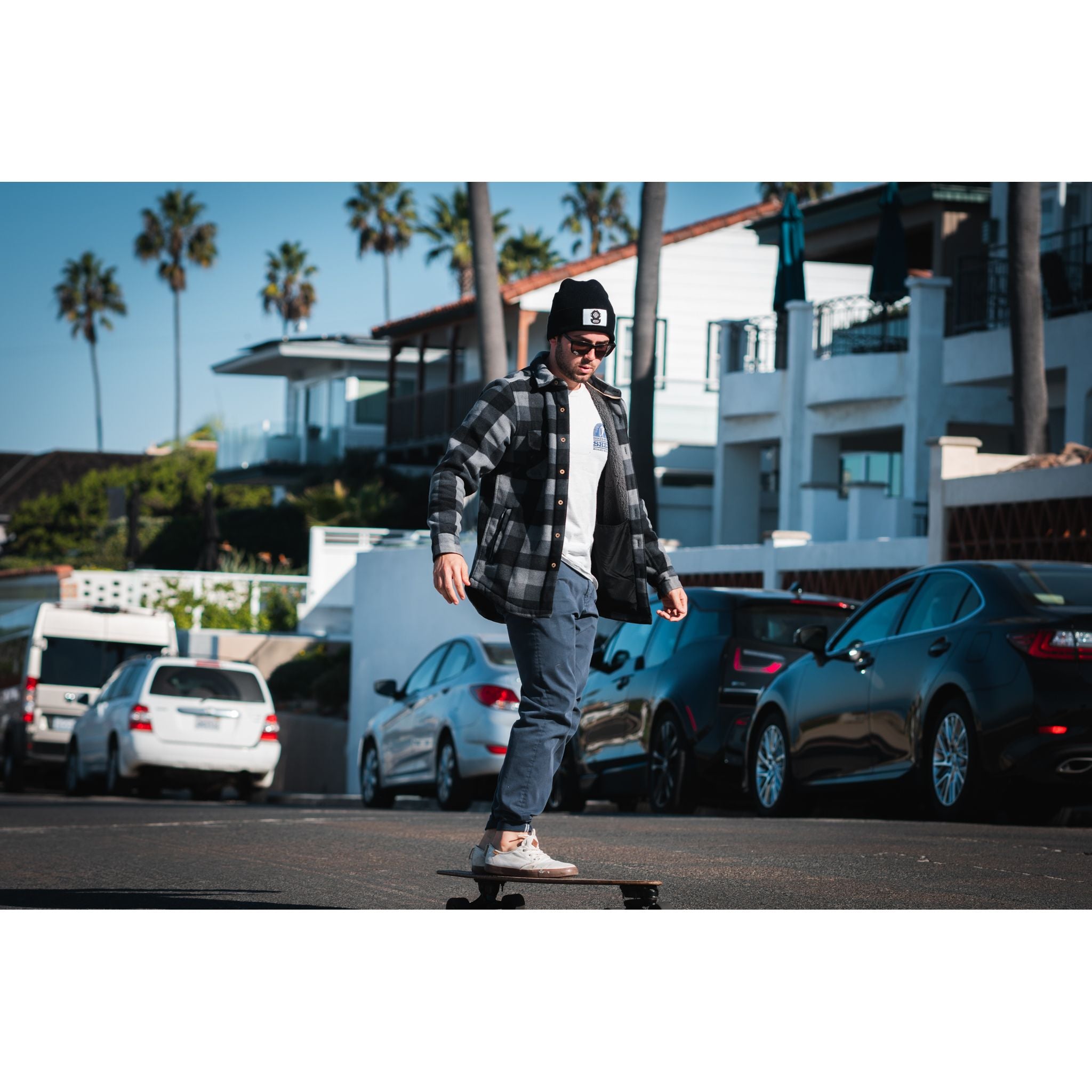 The Watch Cap - man wearing black beanie while skateboarding down the street