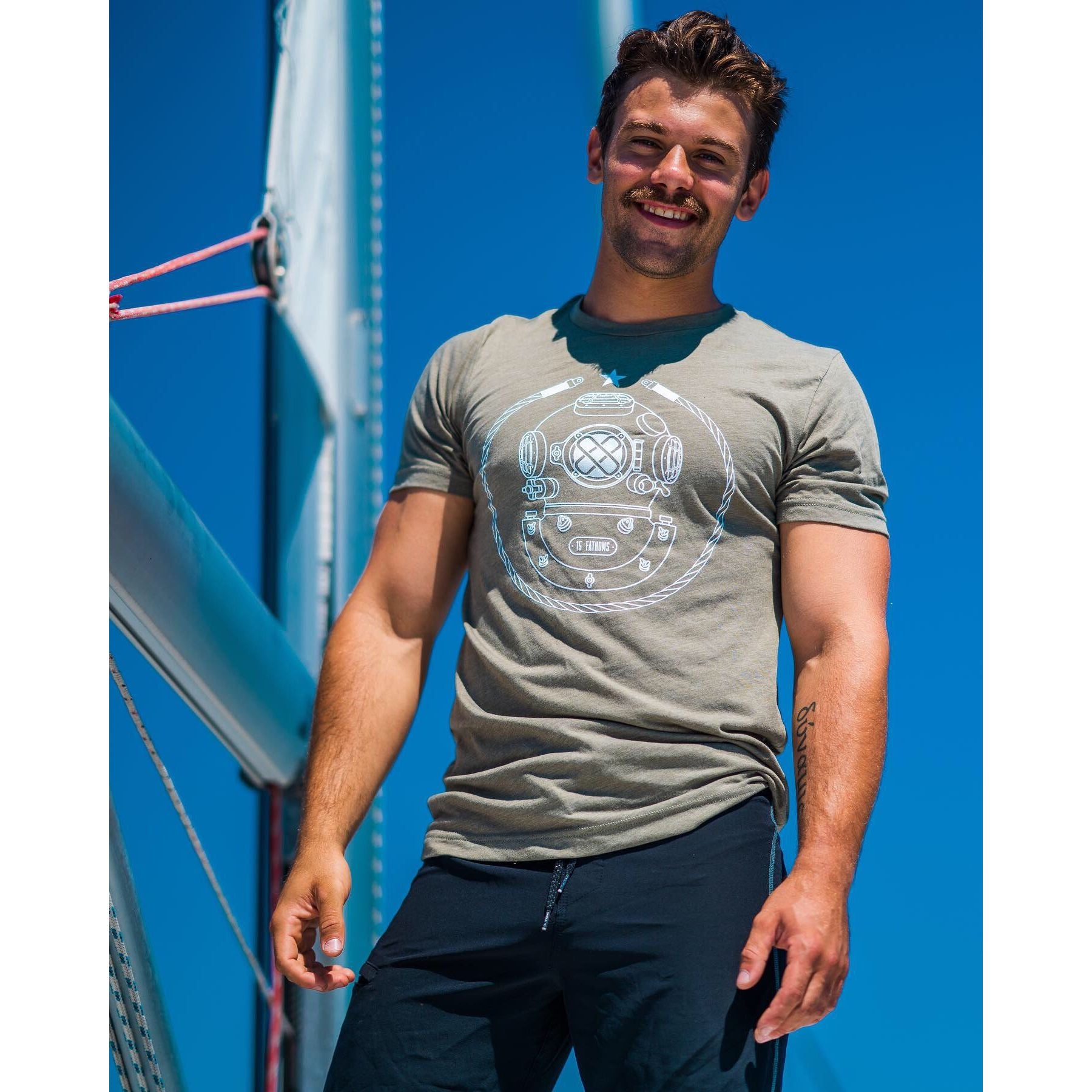 Iconic MK-5 T-shirt - smiling man wearing olive t-shirt with white diver helmet logo on front on a sunny day